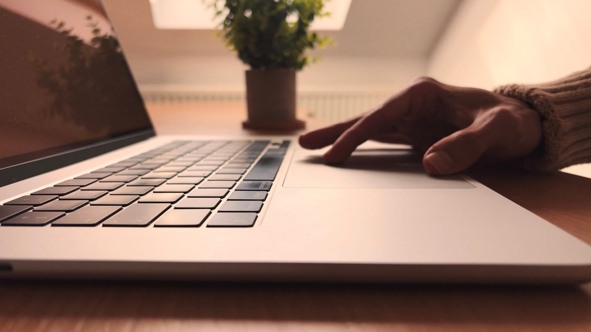 Bhavesh pressing the trackpad of his MacBook Air M2 with a plant in the background.